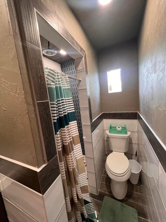 434 Long St, Hereford, TX 79045 - bathroom with toilet, curtained shower, wainscoting, and tile walls