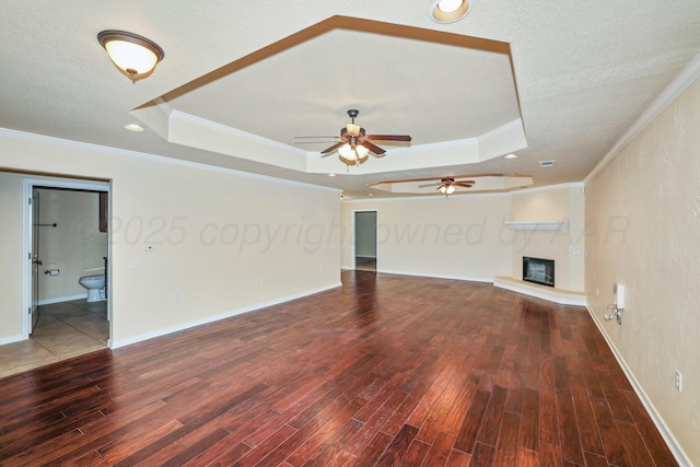 8403 Irvington Ct, Amarillo, TX 79119 - unfurnished living room with a tray ceiling, wood finished floors, ceiling fan, a glass covered fireplace, and ornamental molding