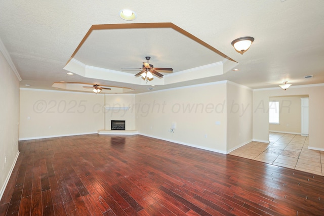 8403 Irvington Ct, Amarillo, TX 79119 - unfurnished living room featuring a tray ceiling, wood-type flooring, crown molding, ceiling fan, and baseboards