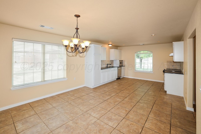 8403 Irvington Ct, Amarillo, TX 79119 - kitchen with appliances with stainless steel finishes, dark countertops, decorative backsplash, a chandelier, and light tile patterned floors