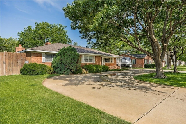 ranch-style home with concrete driveway, brick siding, a front yard, and fence