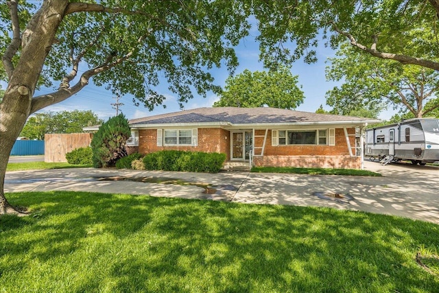 single story home featuring a front yard, fence, and brick siding