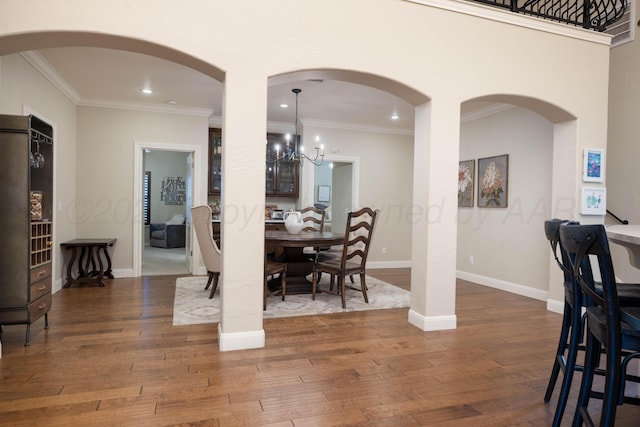 dining space with wood-type flooring, recessed lighting, crown molding, and an inviting chandelier