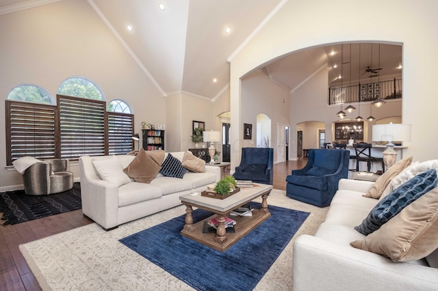 living room with wood finished floors, baseboards, ceiling fan, high vaulted ceiling, and arched walkways