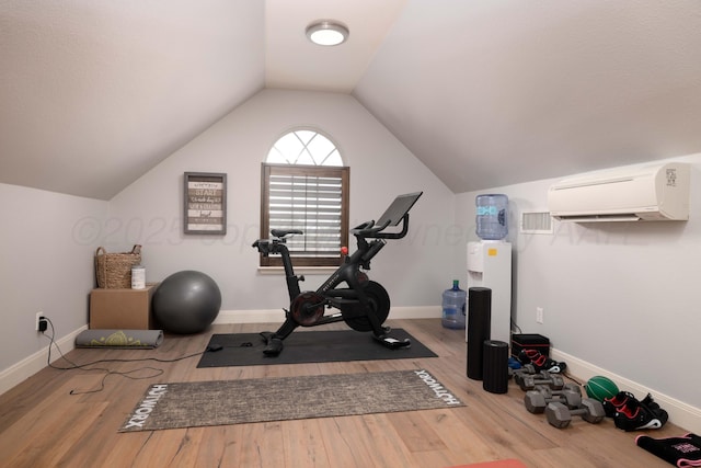 workout room featuring baseboards, a wall mounted AC, wood finished floors, and lofted ceiling
