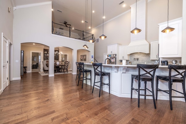kitchen featuring crown molding, arched walkways, a high ceiling, and a ceiling fan