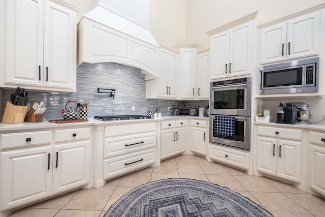 kitchen featuring light countertops, stainless steel appliances, decorative backsplash, and light tile patterned floors
