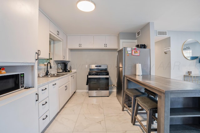 3515 NE 19th Ave, Amarillo, TX 79107 - kitchen featuring stainless steel appliances, a sink, light marble finish floors, white cabinetry, and light countertops
