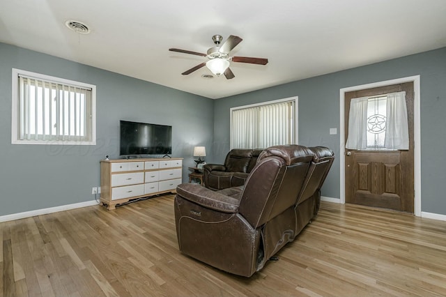 living room featuring light wood-style flooring, plenty of natural light, baseboards, and visible vents