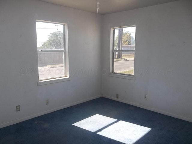 unfurnished room with dark colored carpet and plenty of natural light