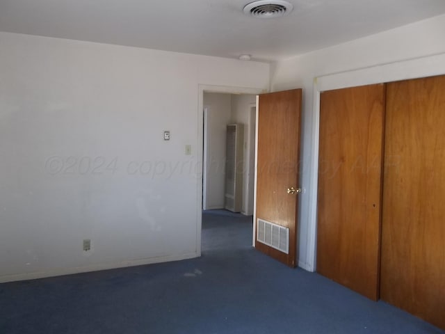 unfurnished bedroom with dark colored carpet and a closet