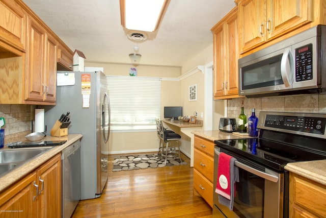 1219 S Rusk St, Amarillo, TX 79102 - kitchen featuring appliances with stainless steel finishes, tasteful backsplash, light countertops, and light wood finished floors