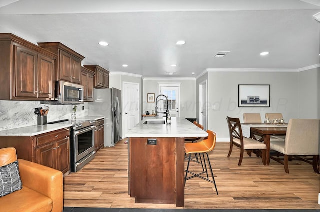 5001 Gloster St, Amarillo, TX 79118 - kitchen with stainless steel appliances, a sink, ornamental molding, light wood finished floors, and a breakfast bar area
