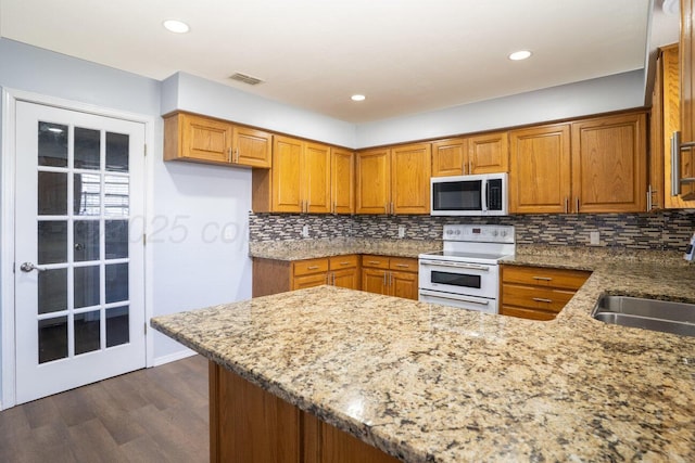 5101 Pin Oak Dr, Amarillo, TX 79110 - kitchen with stainless steel microwave, white electric stove, brown cabinetry, dark wood-style floors, and light stone counters