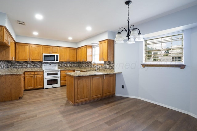 5101 Pin Oak Dr, Amarillo, TX 79110 - kitchen featuring stainless steel microwave, range with two ovens, brown cabinetry, a chandelier, and tasteful backsplash