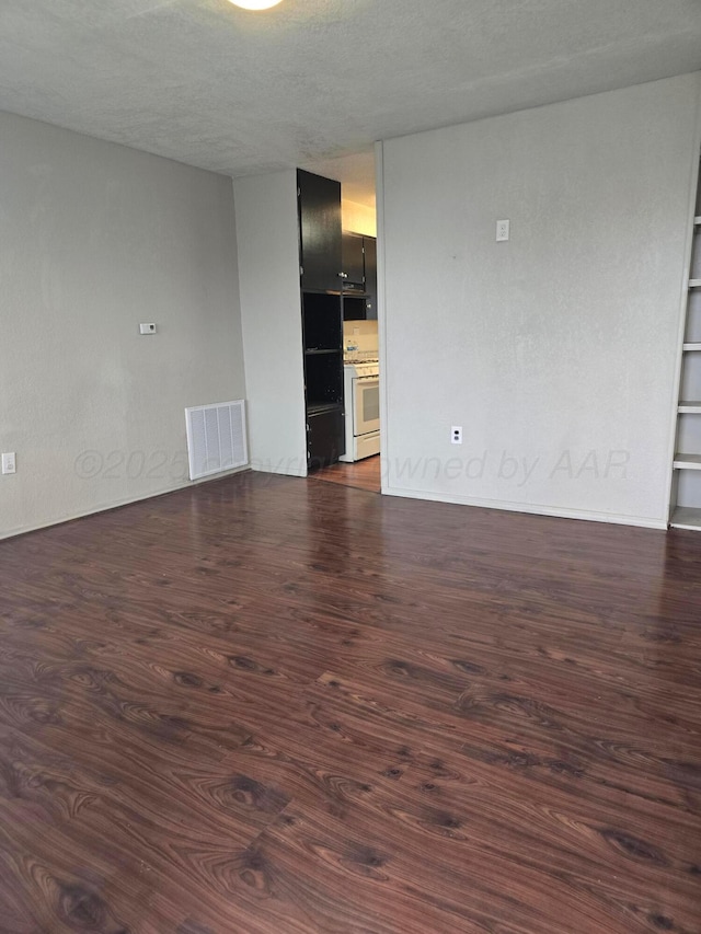 unfurnished room with a textured ceiling and dark hardwood / wood-style flooring