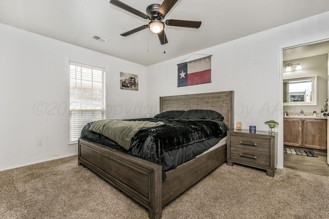 bedroom featuring a sink, visible vents, light colored carpet, ceiling fan, and connected bathroom