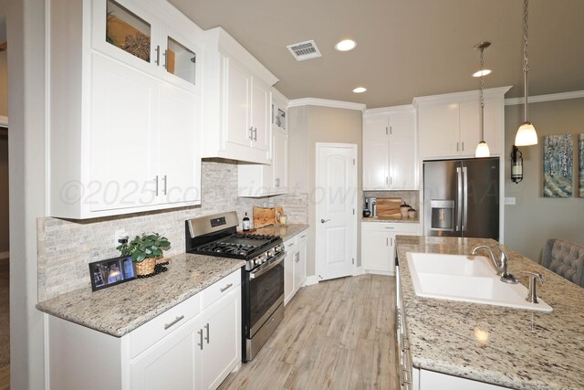 6702 Tatum Cir, Amarillo, TX 79119 - kitchen with appliances with stainless steel finishes, white cabinetry, light wood finished floors, crown molding, and decorative backsplash
