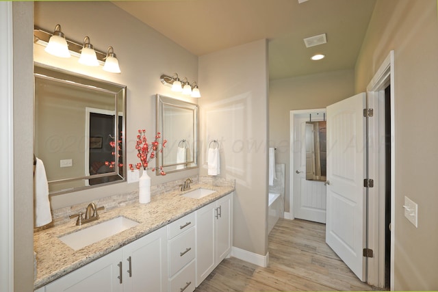 6702 Tatum Cir, Amarillo, TX 79119 - bathroom featuring double vanity, wood finished floors, a garden tub, and recessed lighting