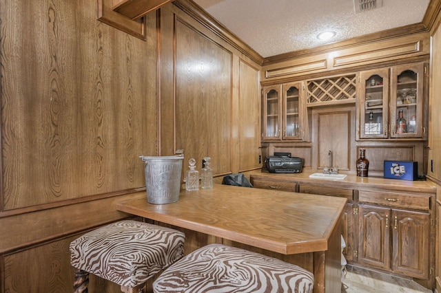 interior space featuring a textured ceiling, wooden walls, butcher block counters, and sink