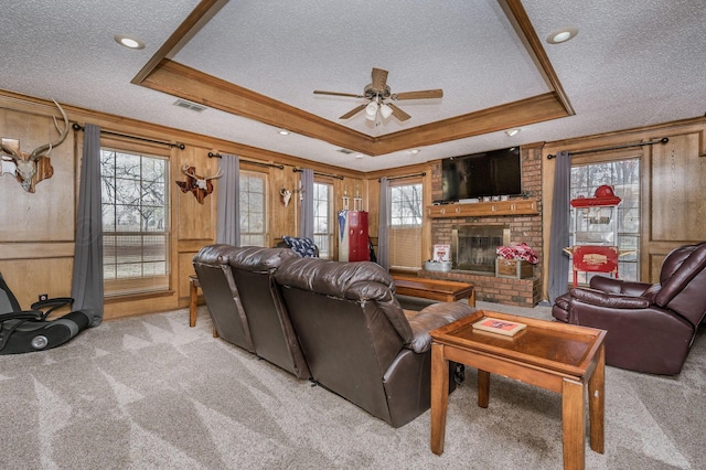 living room featuring a brick fireplace, a textured ceiling, and a tray ceiling