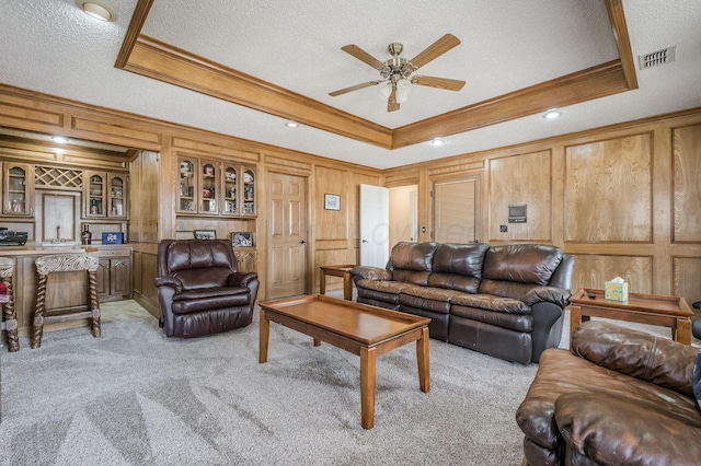 living room with a raised ceiling, a textured ceiling, and light carpet