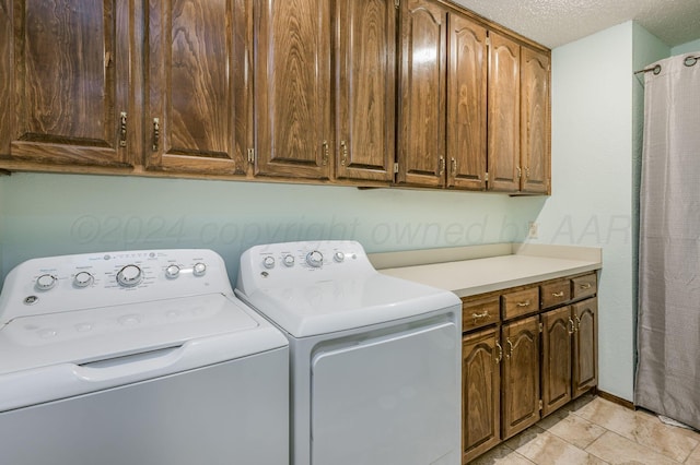 laundry room featuring washer and clothes dryer, cabinets, and a textured ceiling