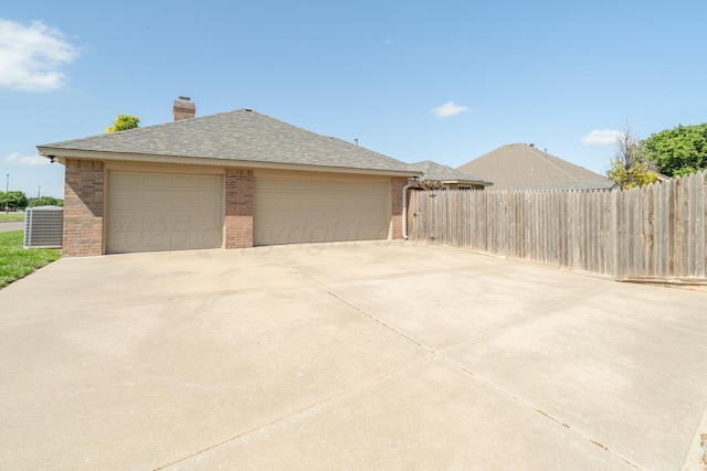 8309 Plymouth Dr, Amarillo, TX 79119 - view of side of home with brick siding, central AC unit, a garage, a chimney, and roof with shingles