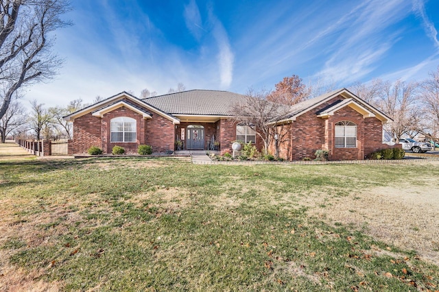 single story home featuring brick siding, a front lawn, and a tiled roof