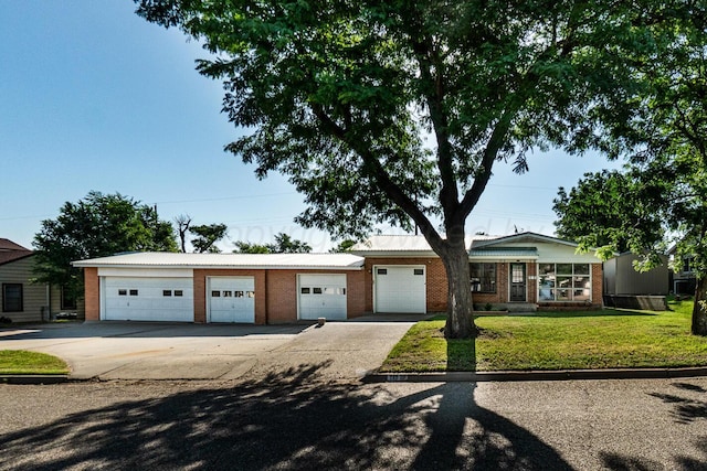 213 Union St, Borger, TX 79007 - ranch-style home featuring brick siding, a front lawn, a garage, concrete driveway, and a metal roof