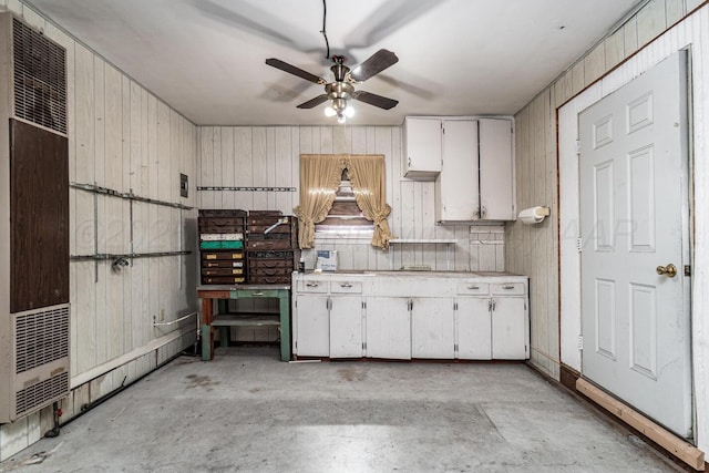 213 Union St, Borger, TX 79007 - kitchen featuring a heating unit, concrete floors, light countertops, wooden walls, and white cabinetry
