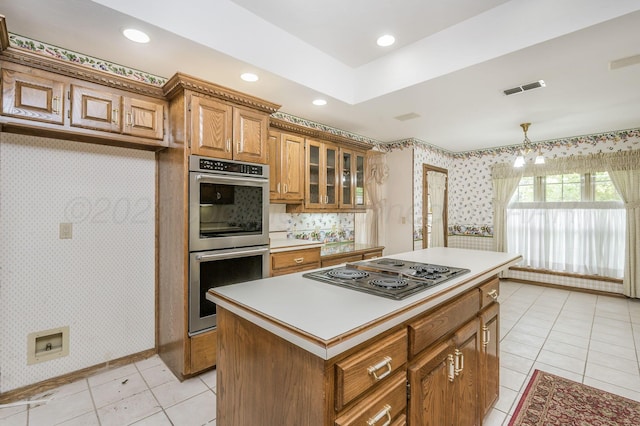 3457 Colchester Pl, Amarillo, TX 79121 - kitchen featuring light tile patterned flooring, wallpapered walls, a center island, brown cabinets, and appliances with stainless steel finishes