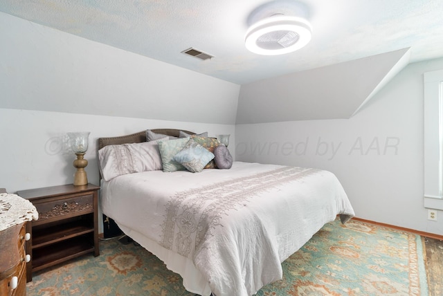 carpeted bedroom with vaulted ceiling, baseboards, and visible vents