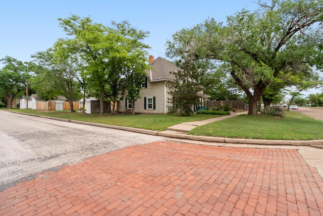 obstructed view of property with a front lawn, a chimney, and fence