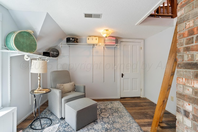 living area featuring visible vents, a textured ceiling, and wood finished floors