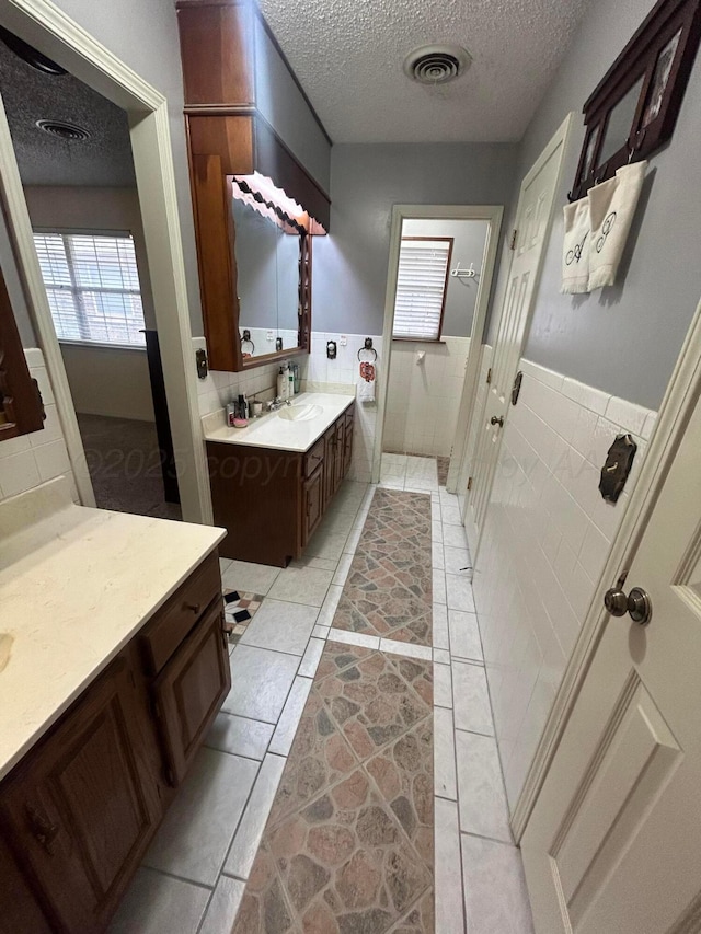7906 Merchant Dr, Amarillo, TX 79121 - bathroom with a wainscoted wall, visible vents, a textured ceiling, and vanity