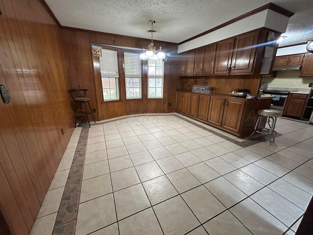 7906 Merchant Dr, Amarillo, TX 79121 - kitchen with wood walls, light tile patterned flooring, a chandelier, a textured ceiling, and stainless steel range with electric stovetop