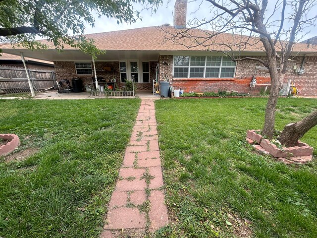 7906 Merchant Dr, Amarillo, TX 79121 - rear view of property featuring fence, a patio area, brick siding, and a yard