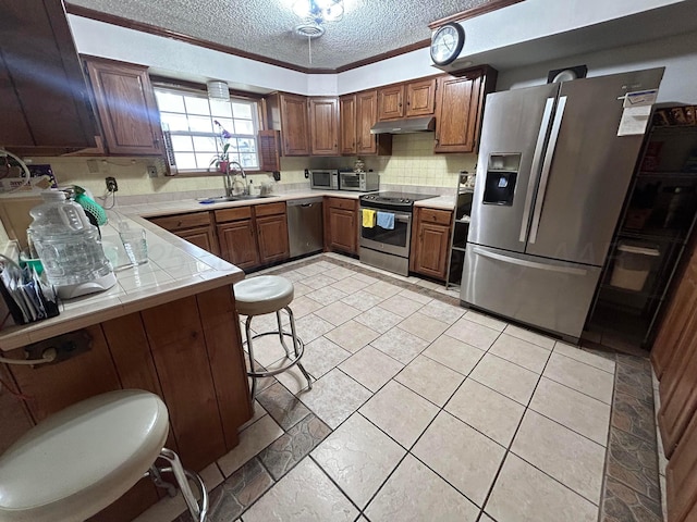 7906 Merchant Dr, Amarillo, TX 79121 - kitchen with tile counters, a sink, decorative backsplash, a textured ceiling, and appliances with stainless steel finishes