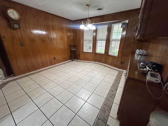 7906 Merchant Dr, Amarillo, TX 79121 - unfurnished dining area featuring a textured ceiling, visible vents, a notable chandelier, wooden walls, and light tile patterned floors
