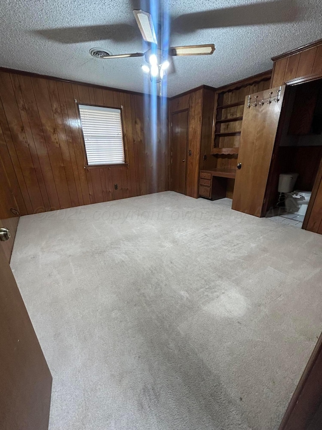 7906 Merchant Dr, Amarillo, TX 79121 - unfurnished bedroom featuring ceiling fan, wood walls, carpet flooring, and a textured ceiling