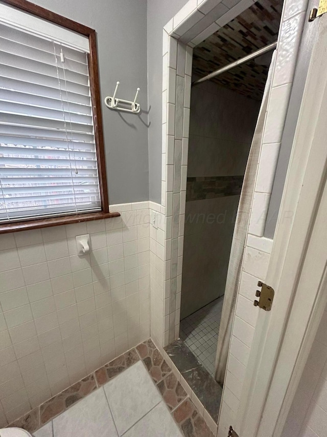 7906 Merchant Dr, Amarillo, TX 79121 - bathroom featuring walk in shower, tile patterned flooring, tile walls, and a wainscoted wall