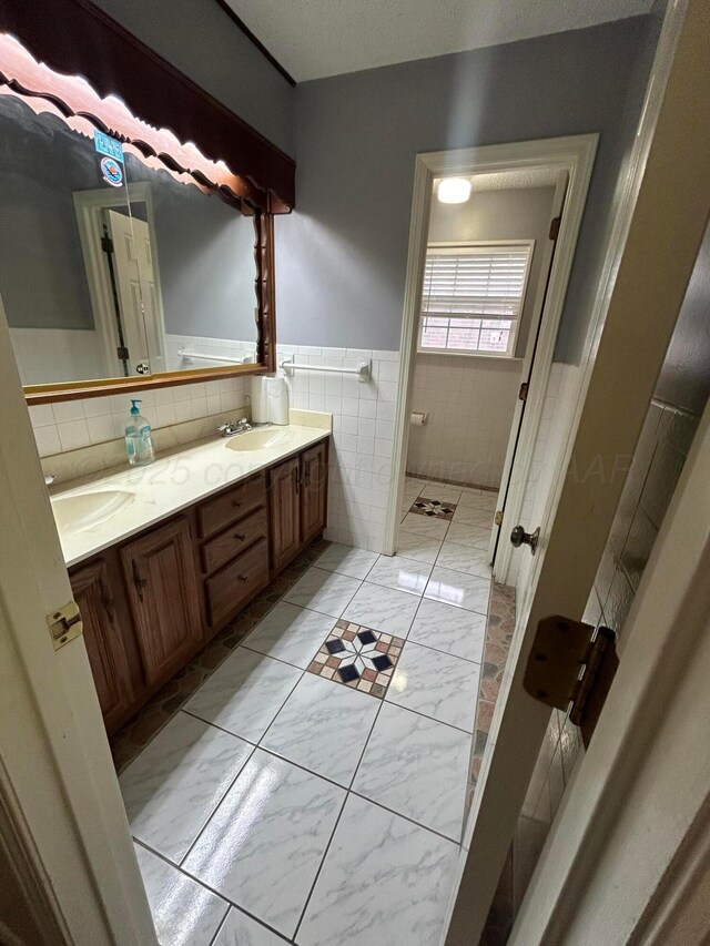 7906 Merchant Dr, Amarillo, TX 79121 - bathroom with marble finish floor, double vanity, a sink, tile walls, and wainscoting