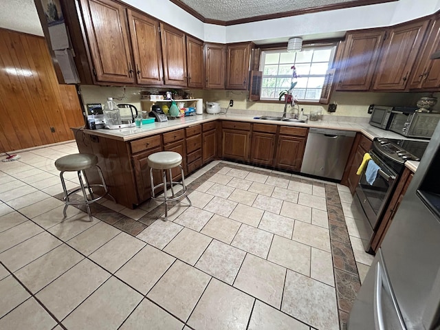 7906 Merchant Dr, Amarillo, TX 79121 - kitchen featuring light countertops, a sink, a textured ceiling, wooden walls, and appliances with stainless steel finishes