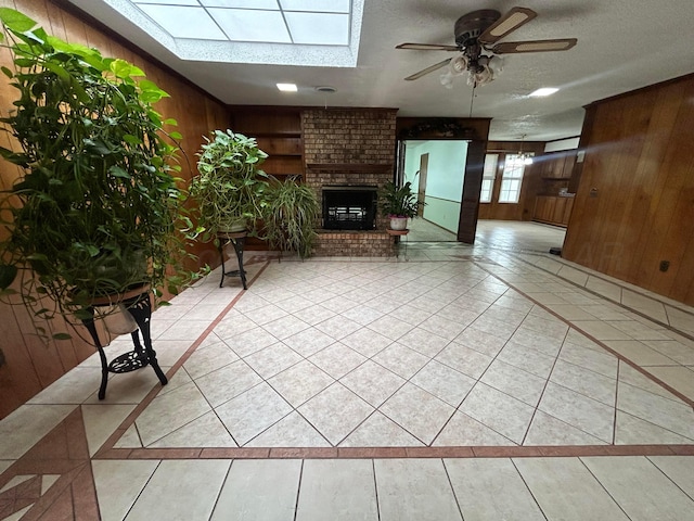 7906 Merchant Dr, Amarillo, TX 79121 - living area with a skylight, light tile patterned flooring, ceiling fan, wood walls, and a brick fireplace