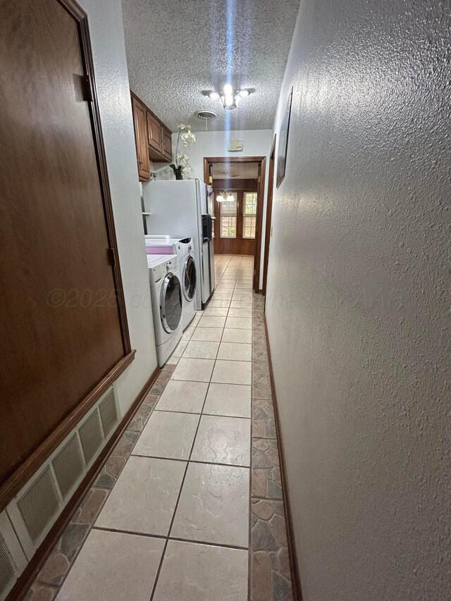 7906 Merchant Dr, Amarillo, TX 79121 - washroom featuring a textured ceiling, light tile patterned flooring, a textured wall, cabinet space, and independent washer and dryer