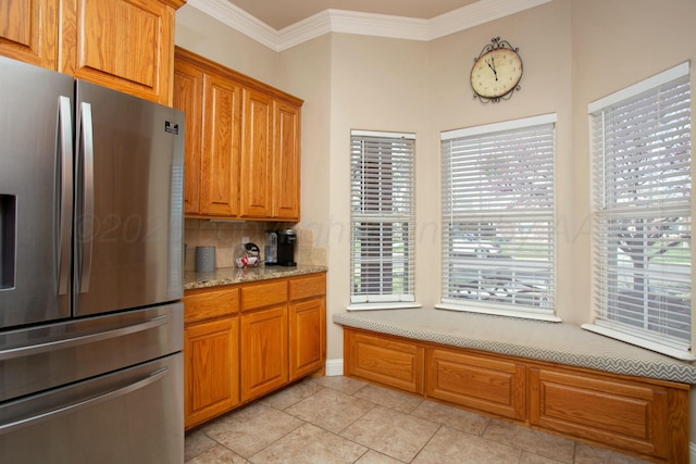 8103 El Paso Dr, Amarillo, TX 79118 - kitchen with stainless steel fridge, crown molding, brown cabinetry, tasteful backsplash, and light stone counters