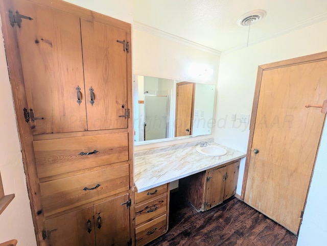 bathroom with ornamental molding, vanity, a shower with shower door, and wood-type flooring