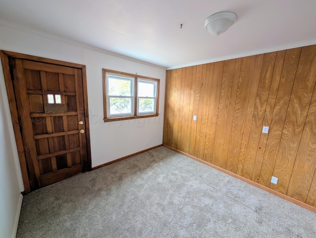 spare room featuring wood walls, crown molding, and light colored carpet