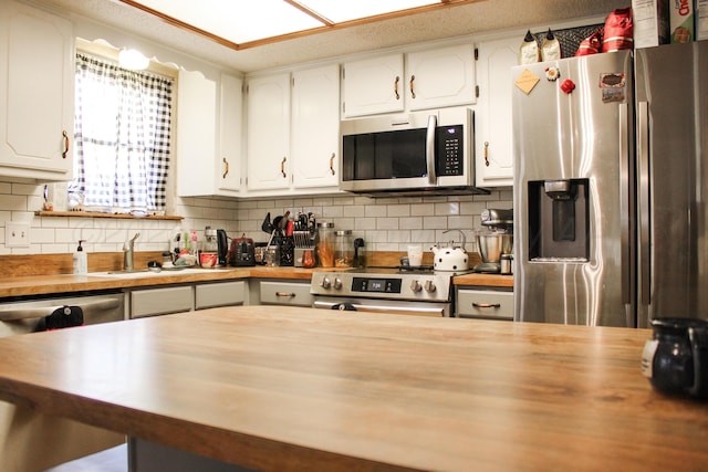 kitchen featuring backsplash, appliances with stainless steel finishes, white cabinets, and wood counters